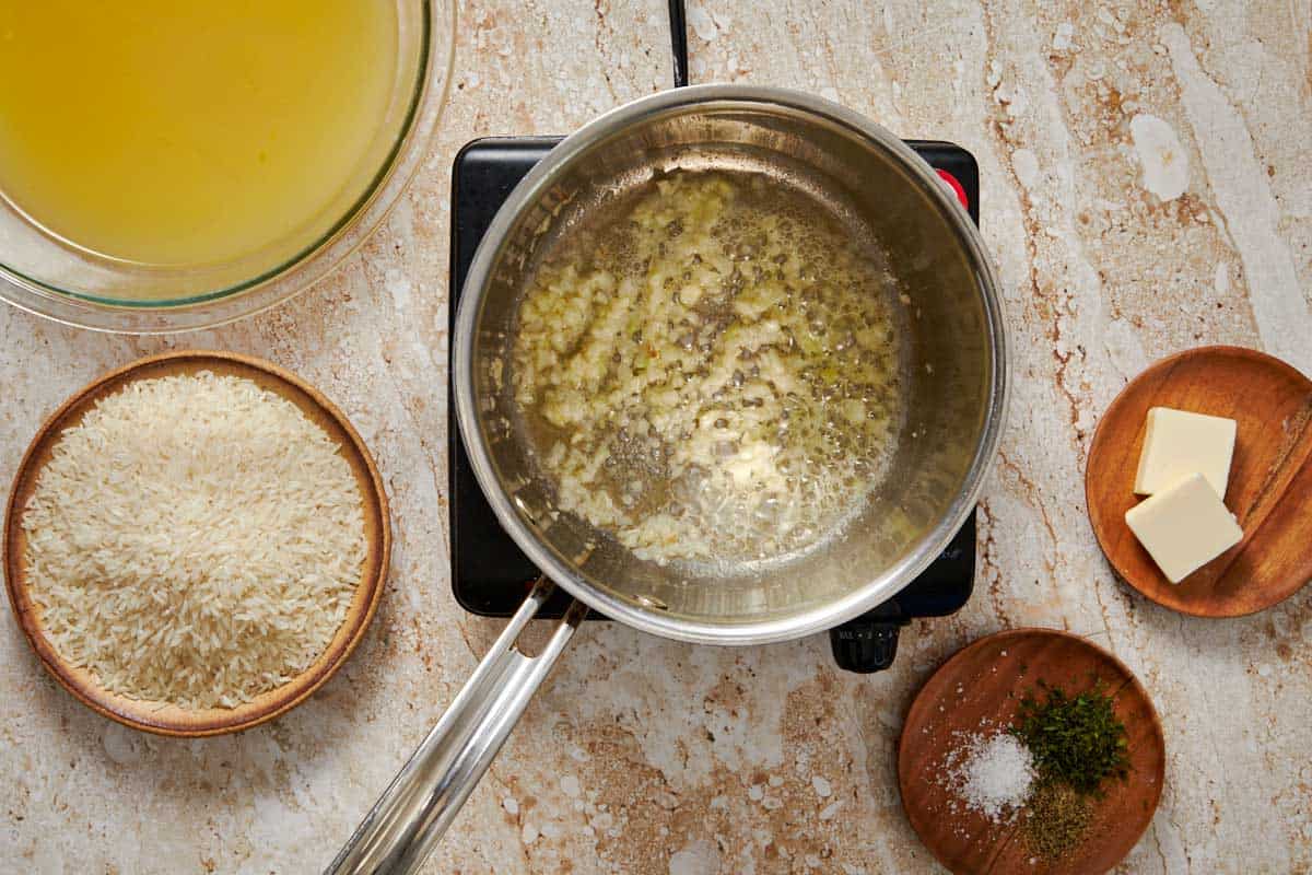 pot on a stove with garlic and butter being saute'd and melted