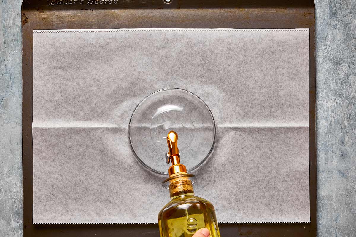 a glass bowl upside down being oiled on a baking tray
