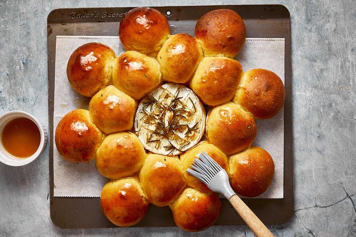 a baked wheel of camembert on a baking tray surrounded by baked bread