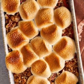 Overhead view of sweet potato casserole with golden toasted marshmallows on top and pecan crumble showing around the edges, fresh from the oven.