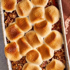 Overhead view of sweet potato casserole with golden toasted marshmallows on top and pecan crumble showing around the edges, fresh from the oven.