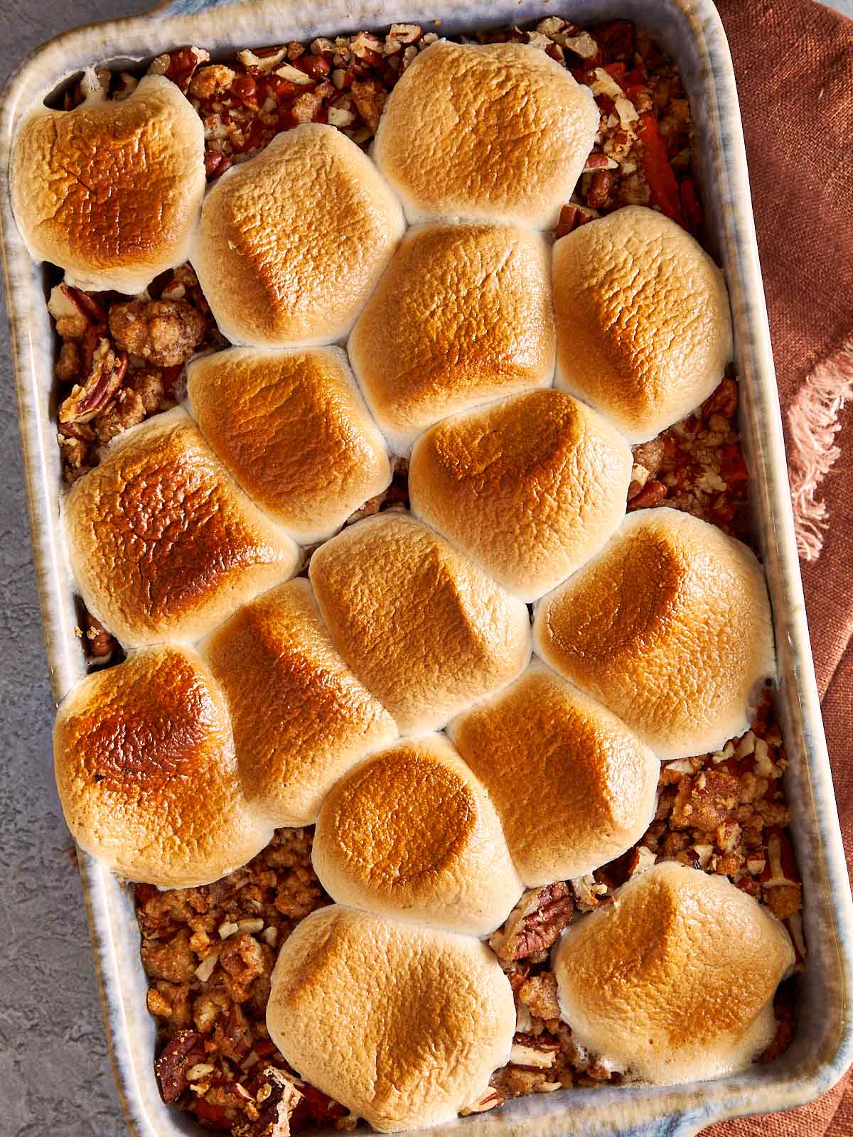 Overhead view of sweet potato casserole with golden toasted marshmallows on top and pecan crumble showing around the edges, fresh from the oven.