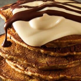 3 pancakes stacked one on top of another, side view, with what looks like greek yogurt on top and drizzling of chocolate coffee on top