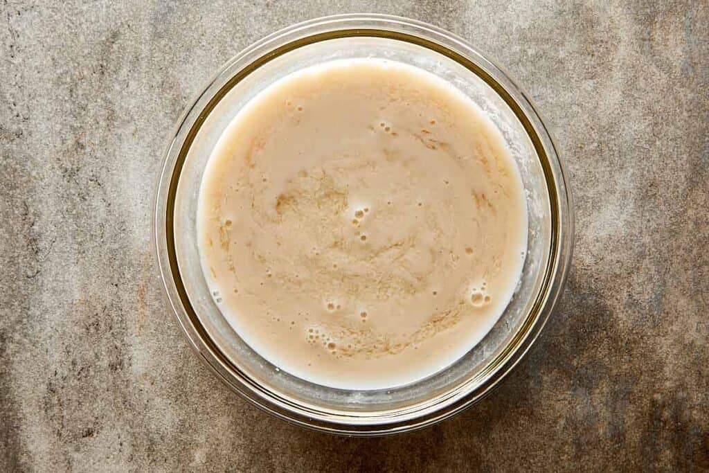 a glass mixing bowl sitting on a bench with pancake mix inside