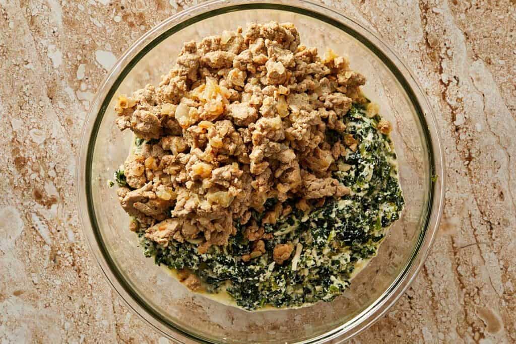 a clear bowl of ricotta cheese and herbs sitting on a bench ready to be mixed