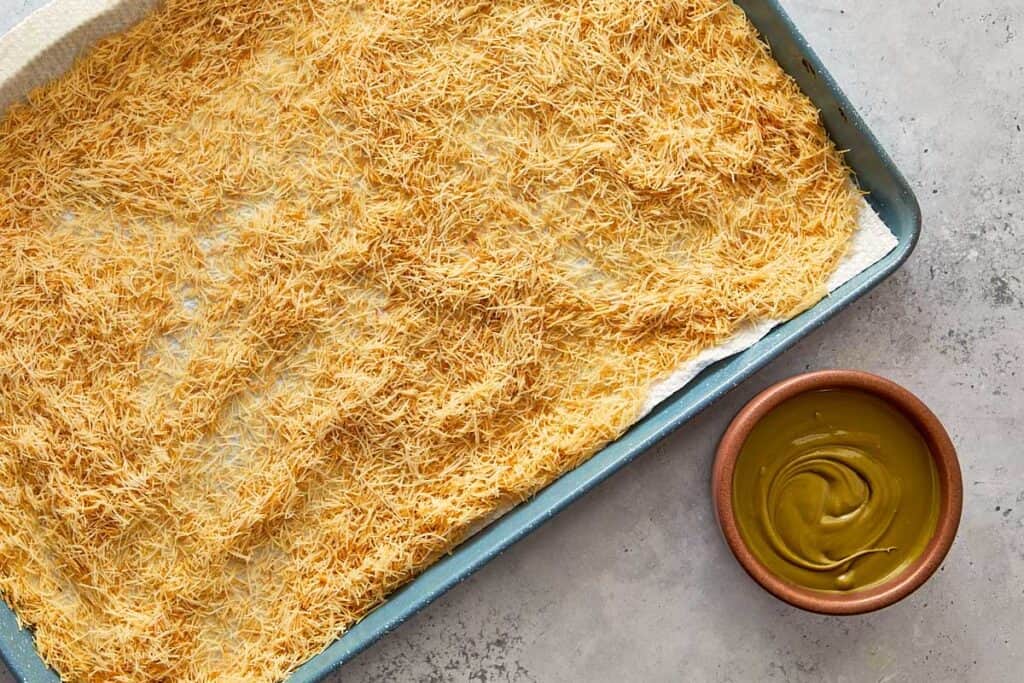 cooking the kadaïf in a tray on the bench