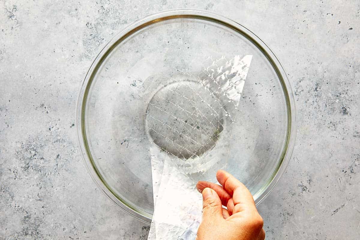 soaking geletin sheets in a clear bowl with water in it, top down view