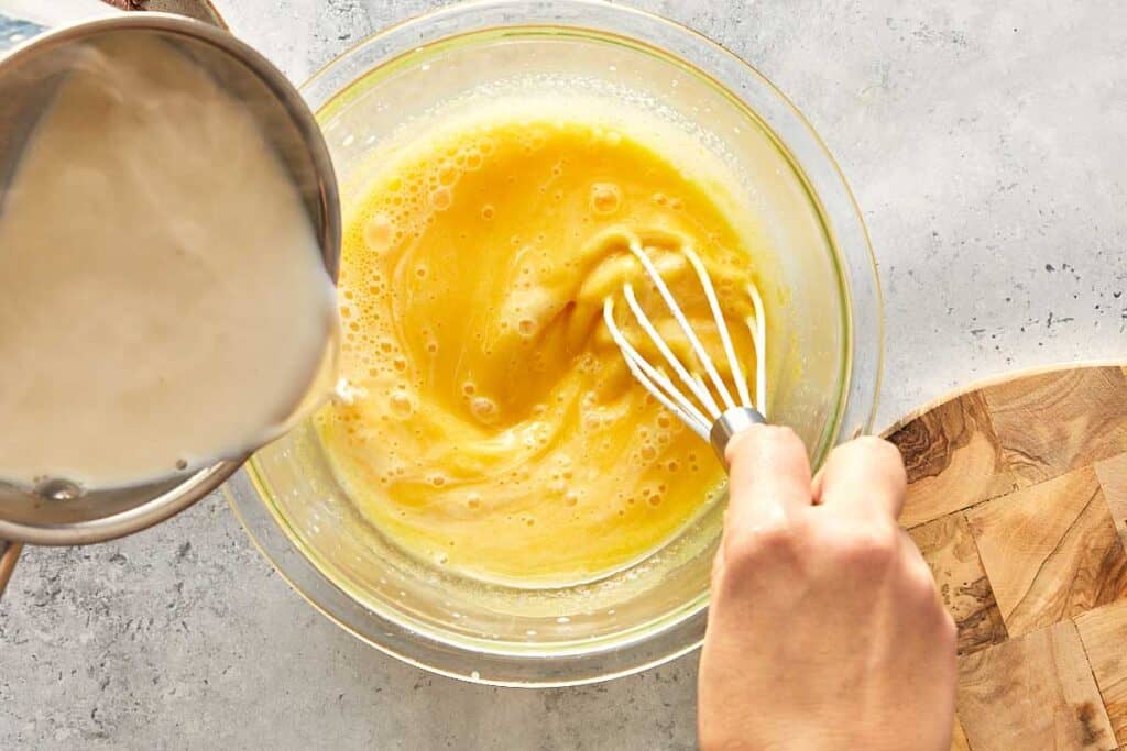 a mixture of egg and cream turning a yellow colour and adding custard into the down from a pot
