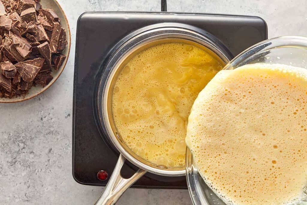 a pot of custard and cream being placed into the custard sitting on top of a cooktop