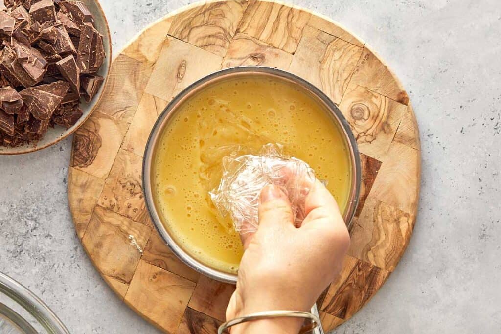 adding sheets of gelatin inside the custard mix on top of a board, the custard is in a pot