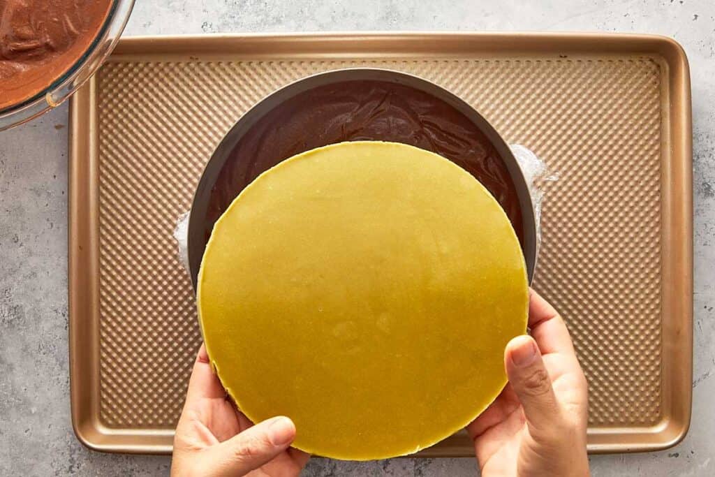 placing a pistachio frozen disk into the cake to create a layer