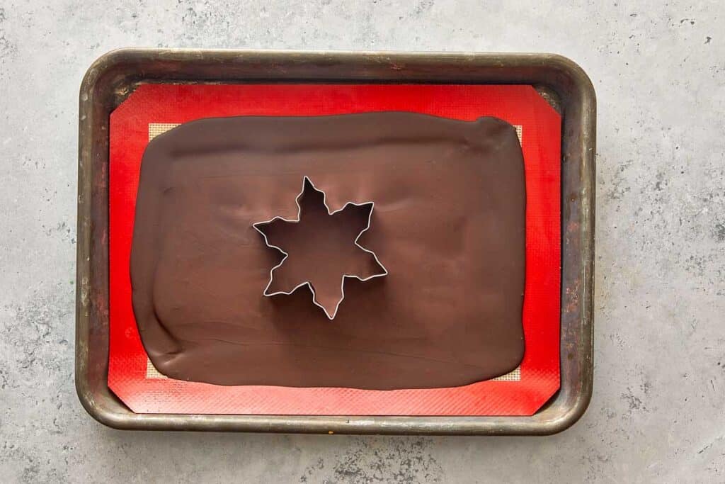 a star being cut into a large sheet of chocolate, it looks like a cookie cutter in the shape of a star