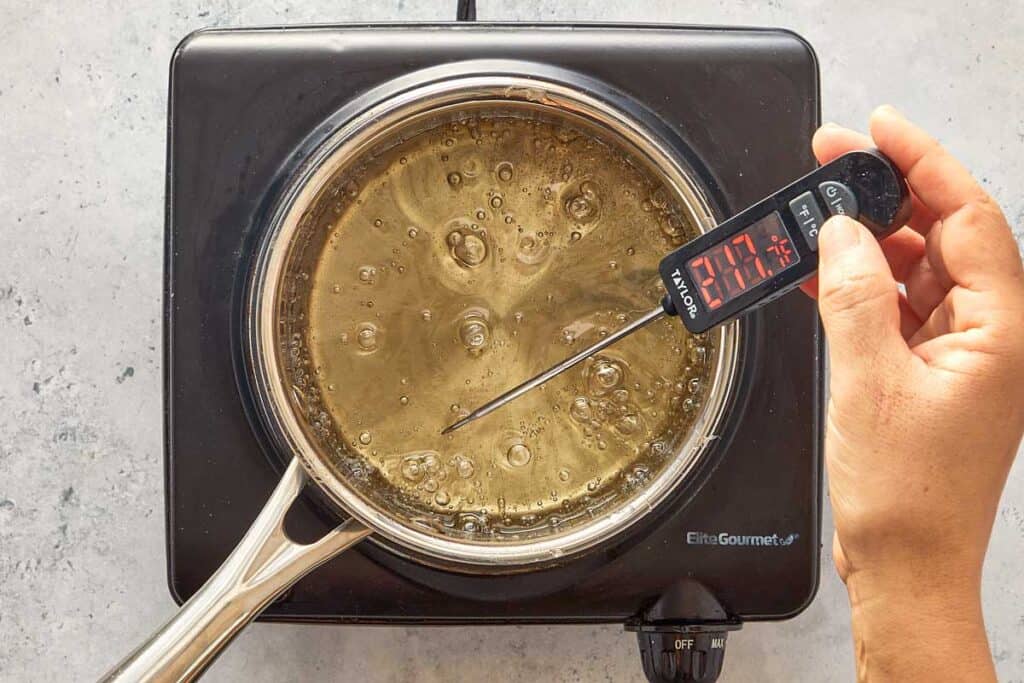 the gelatin sheets being boiled in a pot with a thermometer measuring the boiling water
