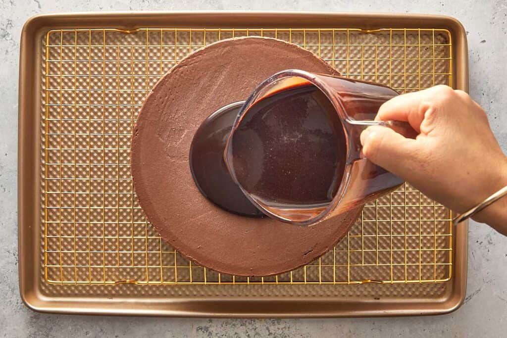 pouring the chocolate glaze on top of the cold mousse cake creating a dark chocolate glaze