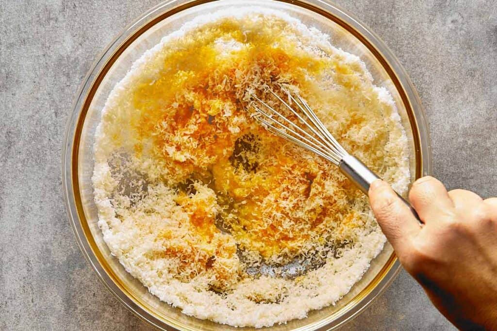 a top down view of a glass bowl with a whisk mixing the dry ingredients and milk - 3
