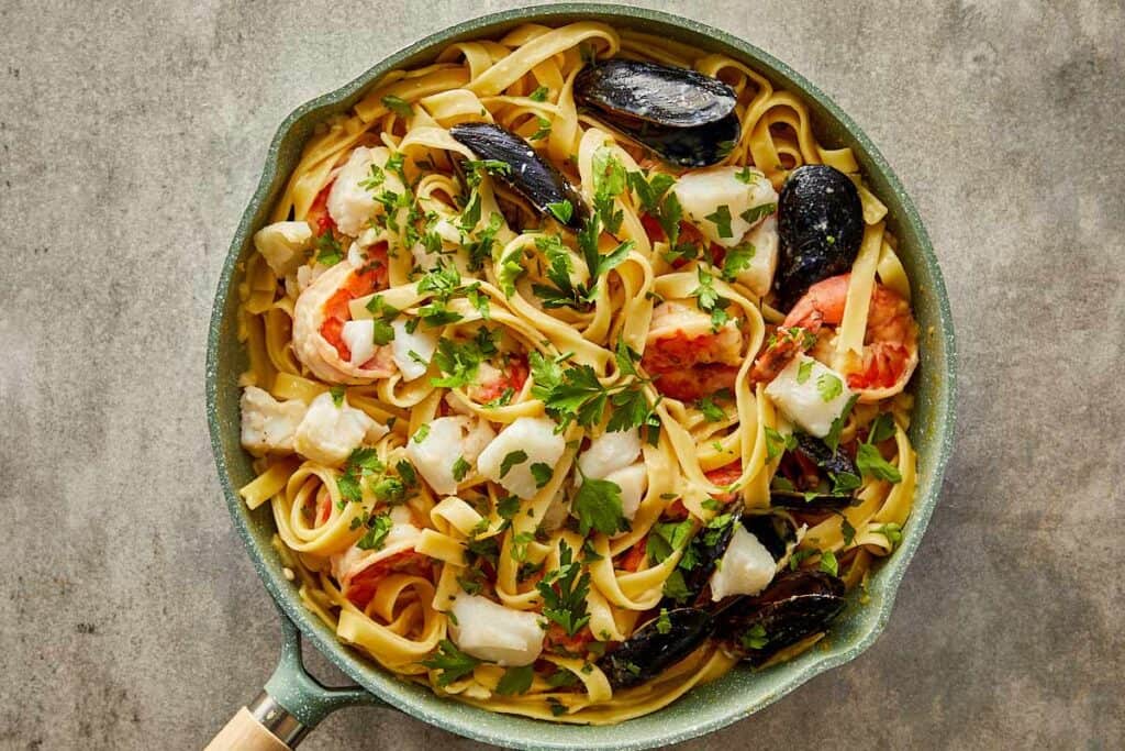 a top down view of seafood and pasta mixed together in a pan - 15