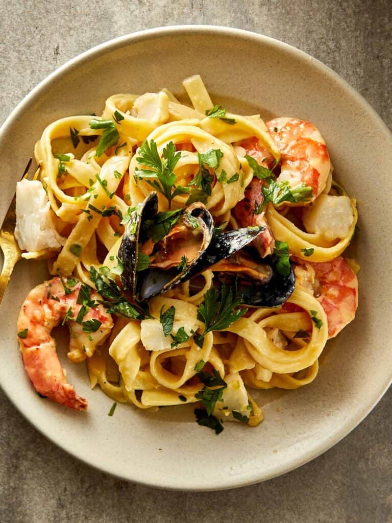 a white plate full of seafood with pasta and seafood - 17