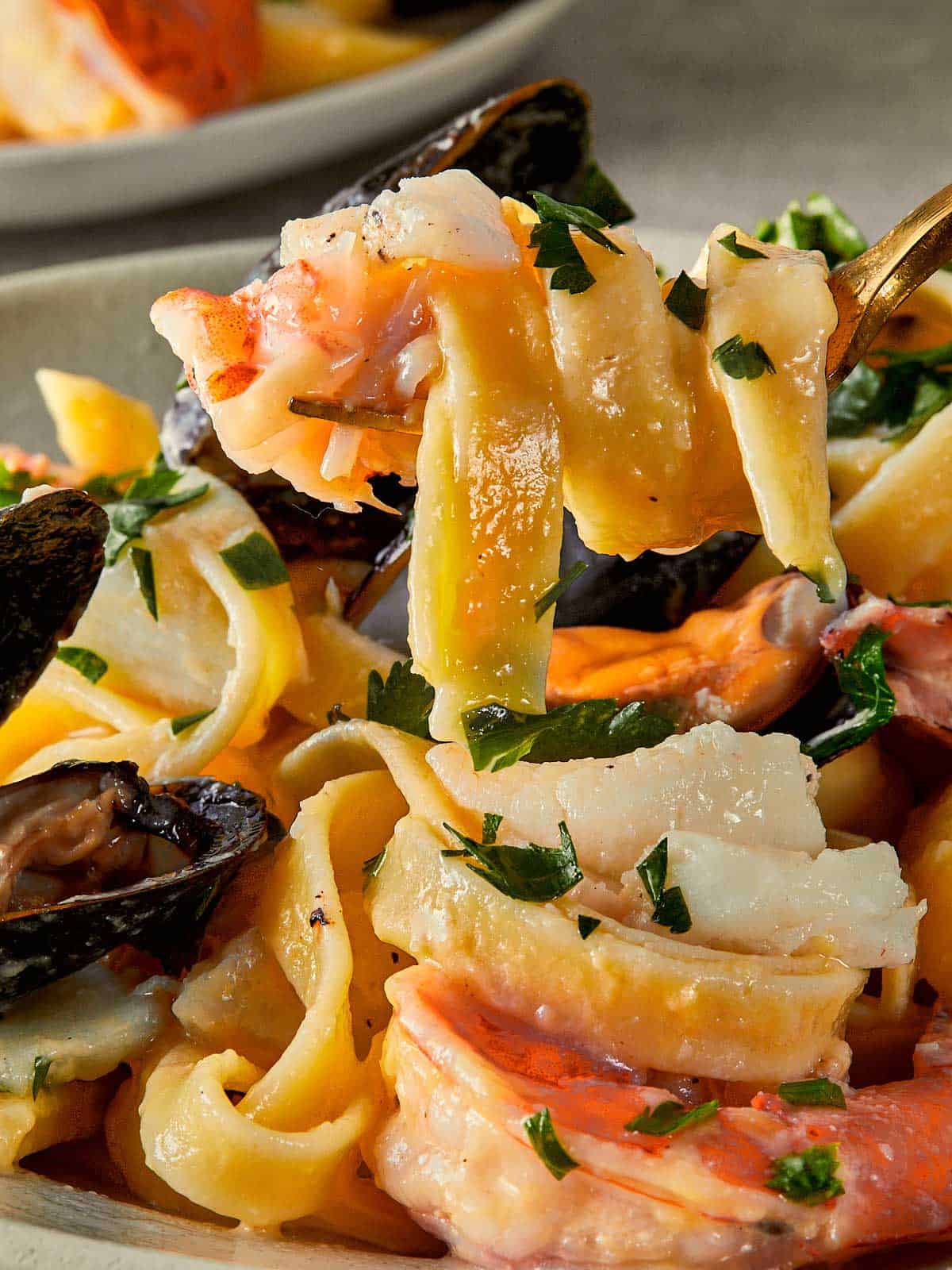 a side view of pasta and sauce and a fork holding the seafood