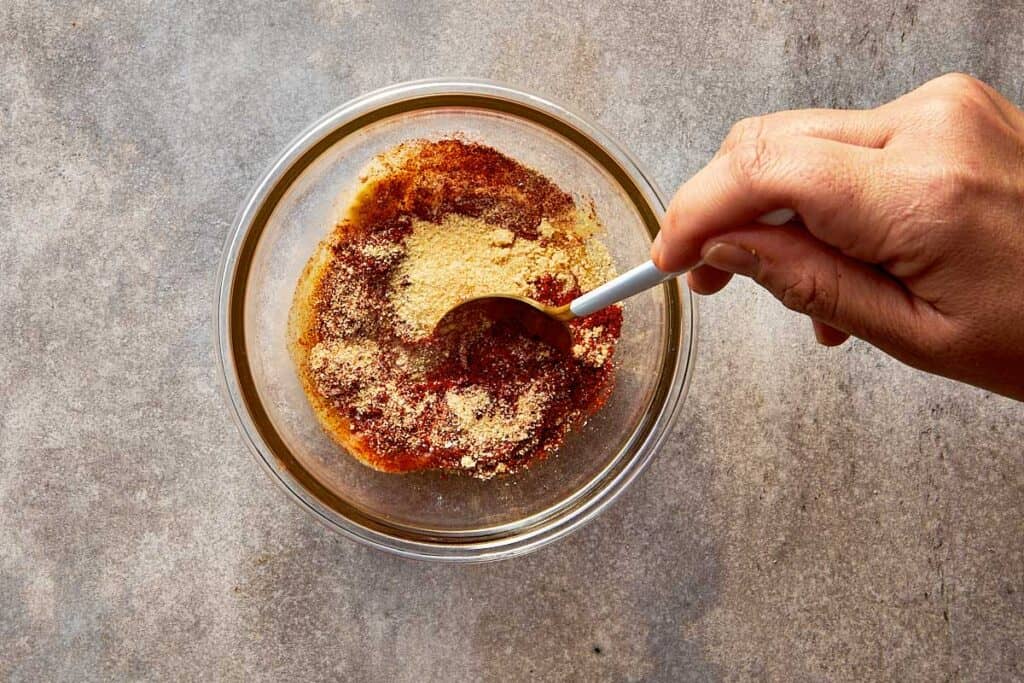 a top down shot of a spoon mixing the spices and egg mix together with a spoon