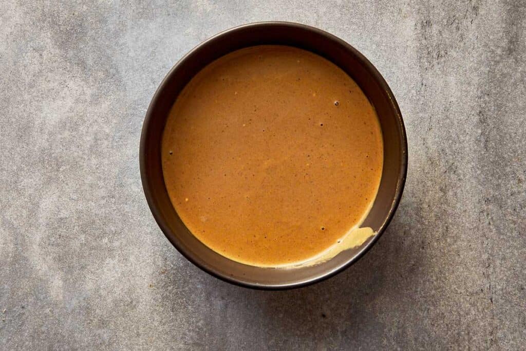 a top down view of a black bowl with sauce inside