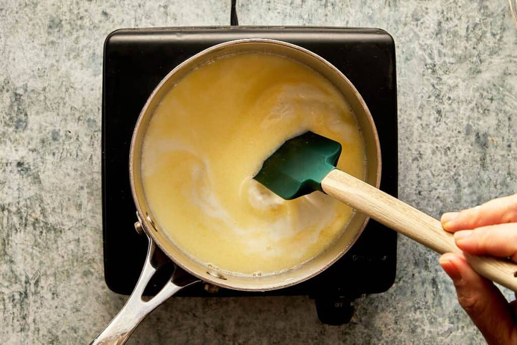 a top down view of a pan of milk and a mixing rubber spoon mixing in the pot - 5