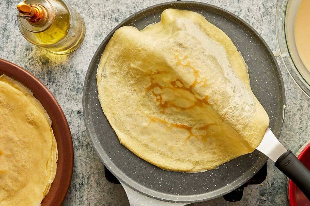 a top down view of a crepe being removed from a pan - 18