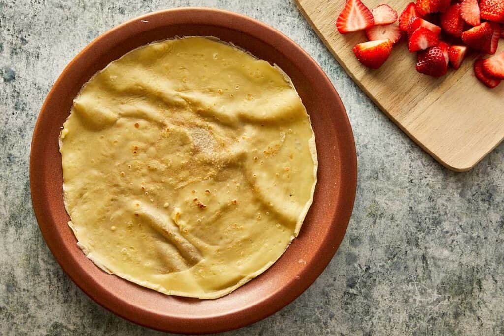 a cooked crepe sitting on top of a ceramic brown plate, the crepe is creased as it sits on the plate - 20