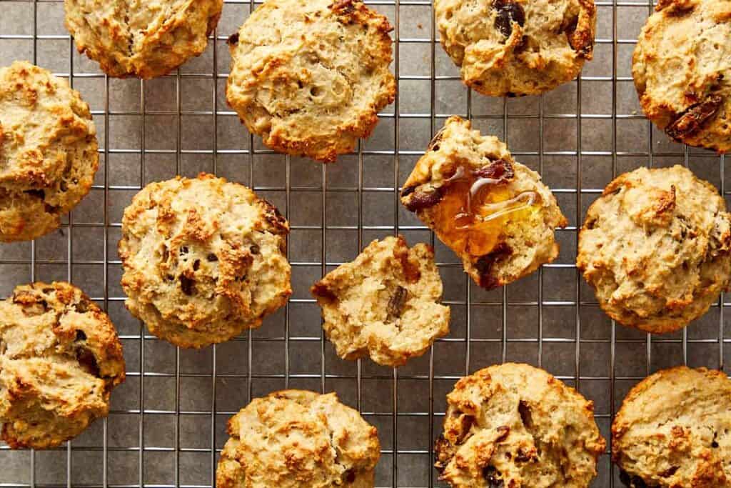 a collection of muffins sitting spaced out on a wire rack cooling with the middle one cut open to show the insides - 12