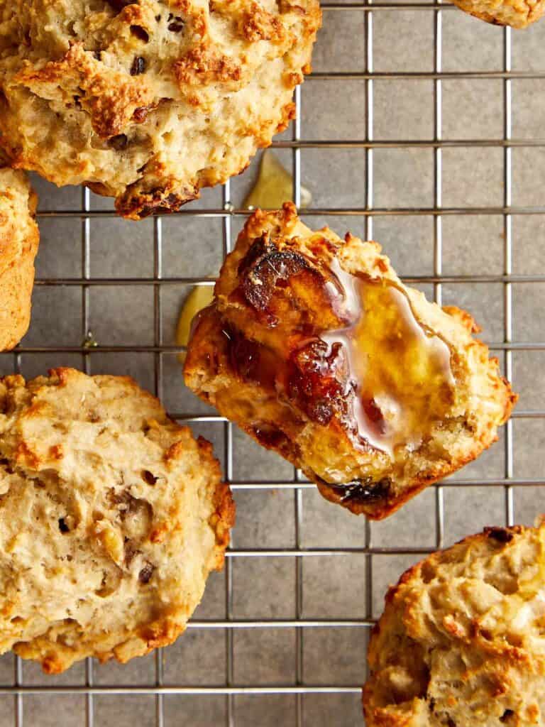 a collection of muffins sitting spaced out on a wire rack cooling close up shot showing honey glazed over half a muffin - 13