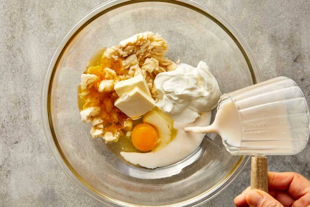 a top down photo of a glass mixing bowl with egg and milk butter and vanilla in it. - 6
