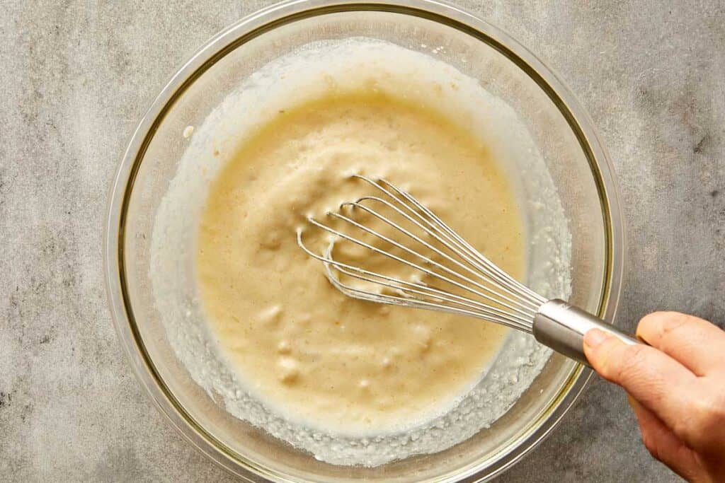 a top down shot of a mixing bowl with a whisk mixing the batter - 7