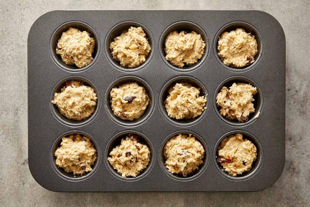 a top down image of raw muffin mix inside each muffin tray ready to be placed in the oven - 10