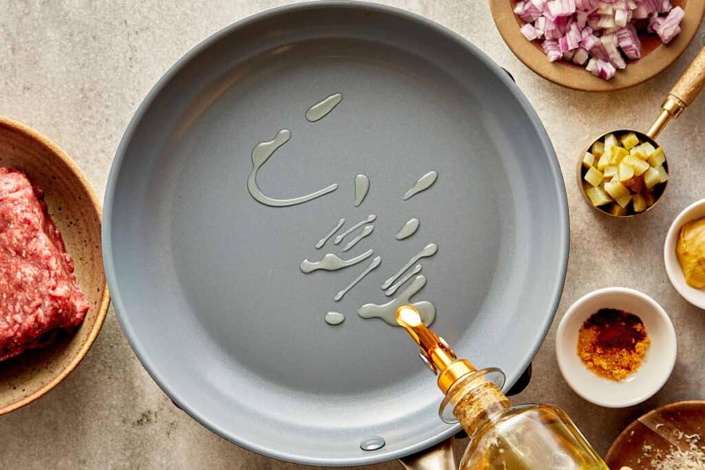 A top down view of a empty pan with olive oil being poured into it. - 3