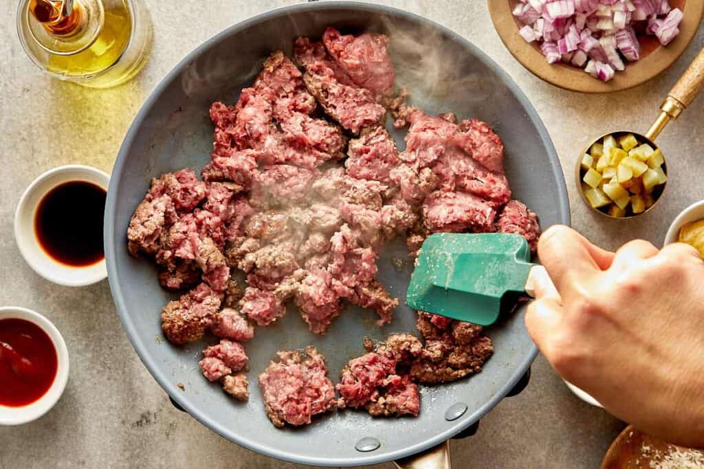 a top down view of a frying pan with mince meat inside being stirred with a spatula - 4