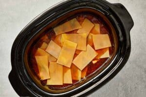 Broken lasagna sheets added on top of simmering soup in a slow cooker