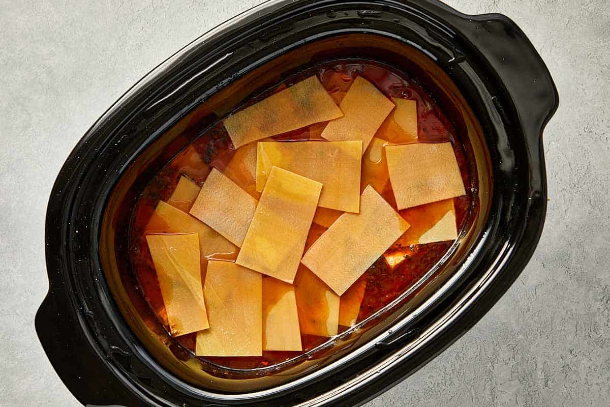 top overview of broke lasagna sheets pieces into the slowcooker  - 11