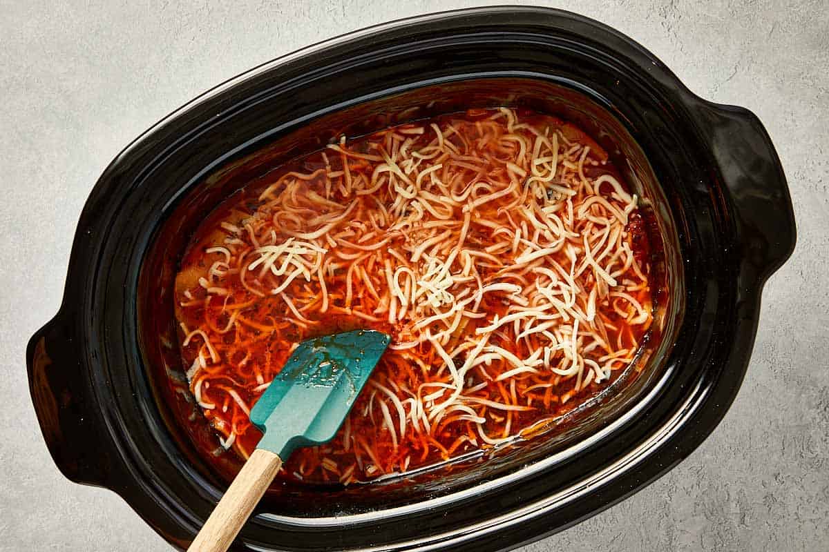 top overview of cheese being added into the lasagna soup in the slowcooker.  - 13