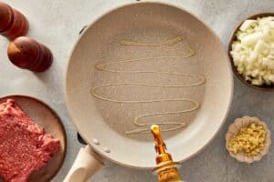 top view of beige pan being drizzle with olive oil