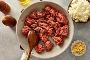 overtop view of beef being cooked in a beige pan