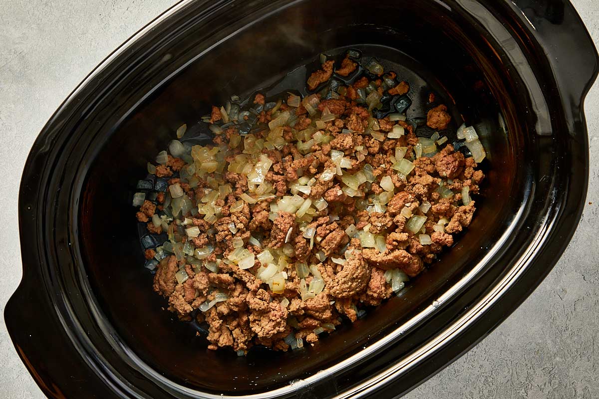 top overview of garlic, onion, vegetables and beef being cooked in the slowcooker - 8