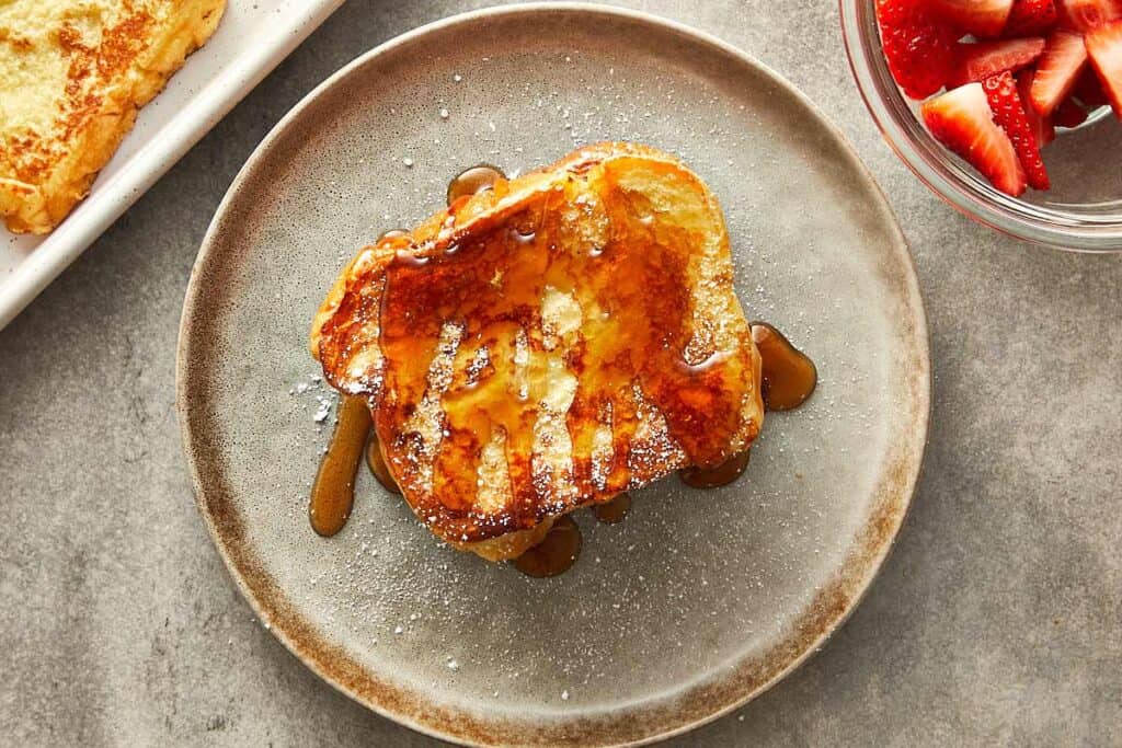 a top down shot of sandwiched brioche toast topped with maple syrup