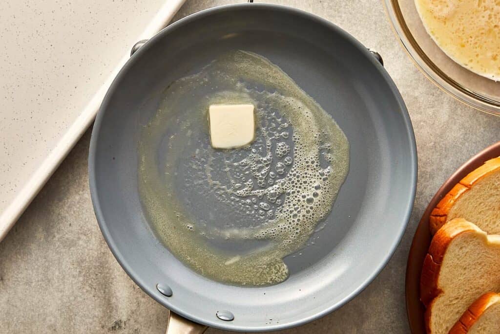 a top down view of a frying pan with a cube of butter melting in the middle.