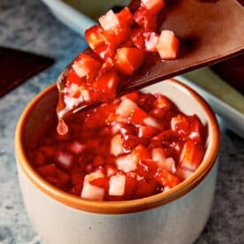 Chocolate chips being dip in the strawberry salsa