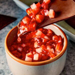 Chocolate chips being dip in the strawberry salsa