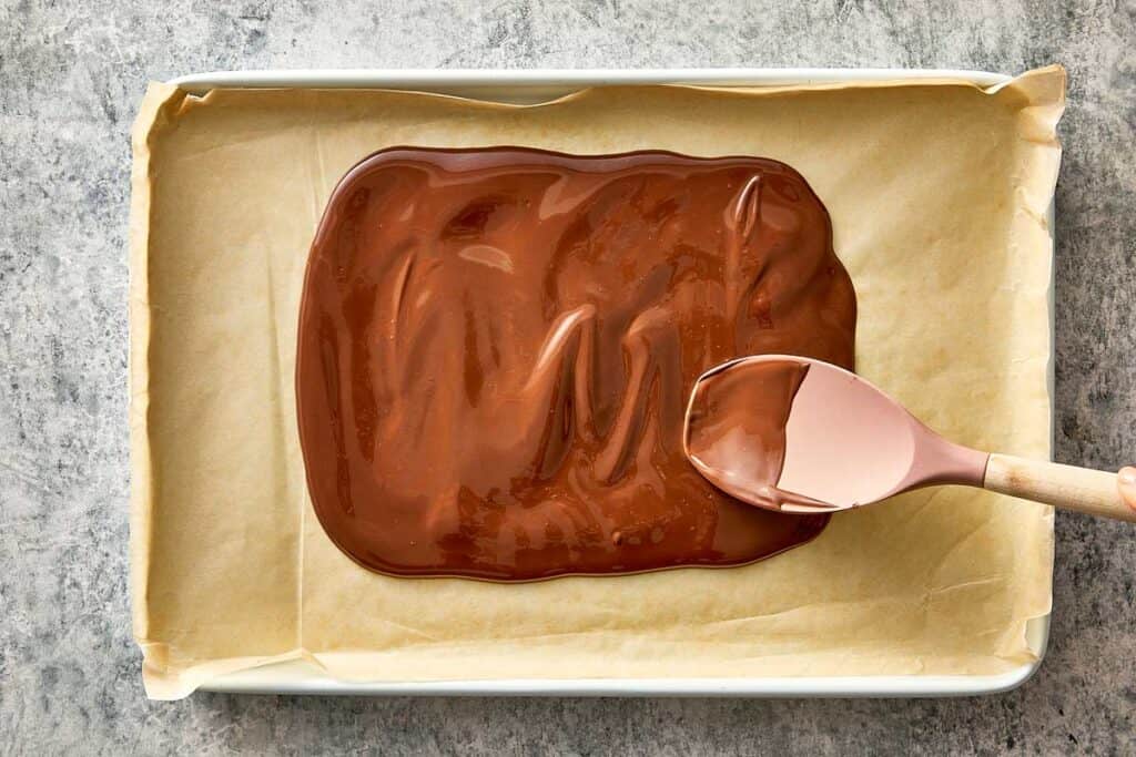 Top overview of melted chocolate being spread into an even layer.
