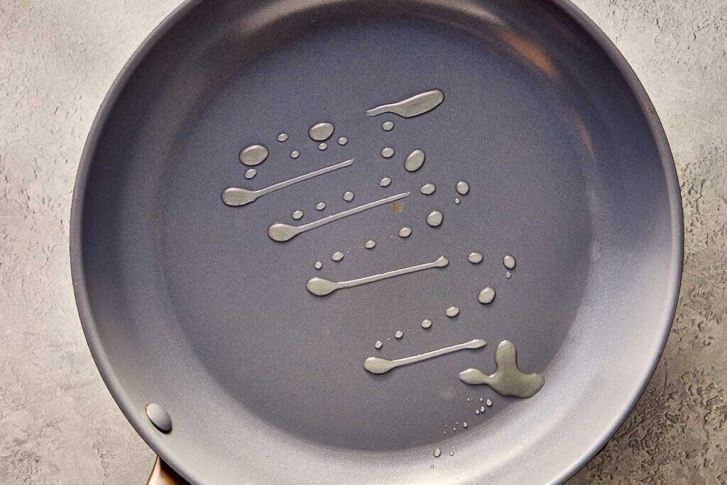a top down image of a frying pan with oil in the middle. The pan is sitting on top of a kitchen bench.