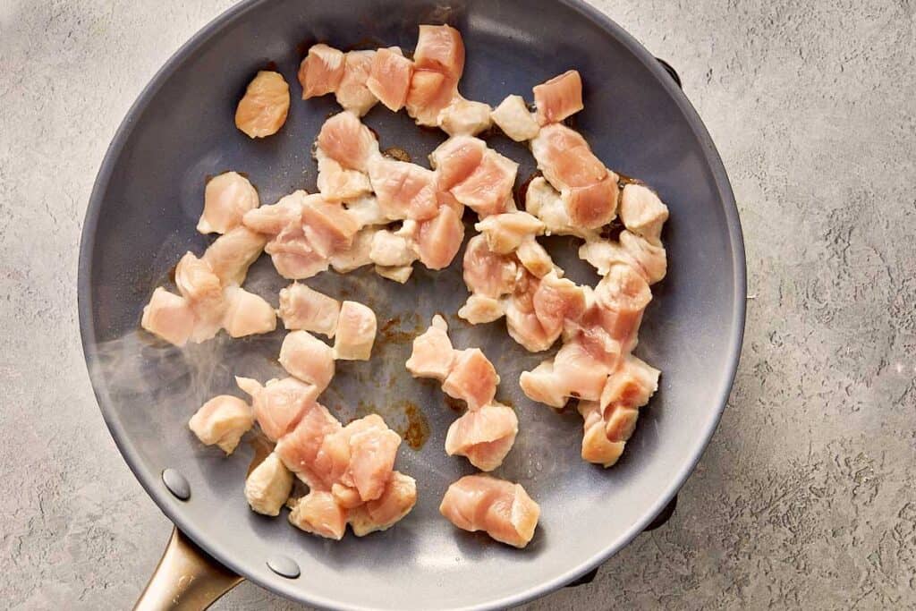 a top down view of a pan with chicken pieces being fried and browned.