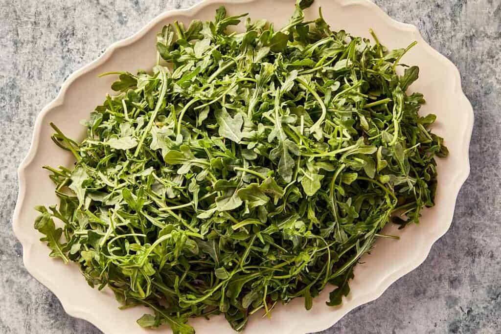 Fresh arugula leaves in a serving bowl, ready to be used for salad.
