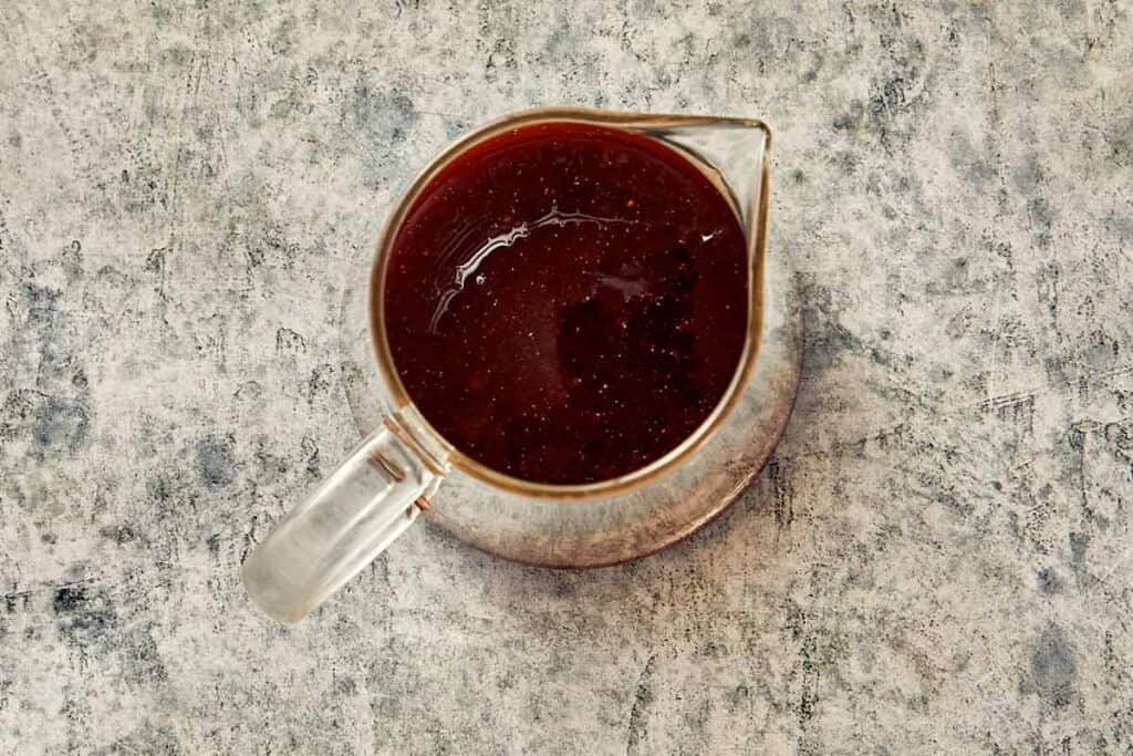 Balsamic glaze dressing in a small glass jug, ready to be used for salad.