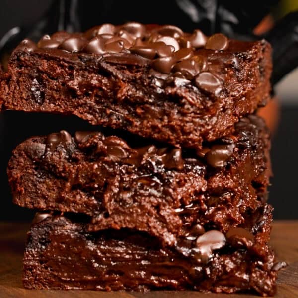side view of the sweet potato brownie stacked up in 3 chunks on a chopping board.